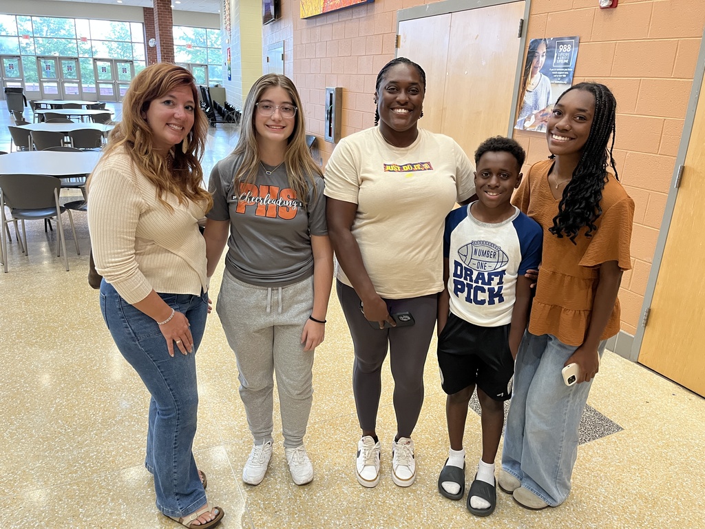 Two adults and three students pose for a photo on a back-to-school night.
