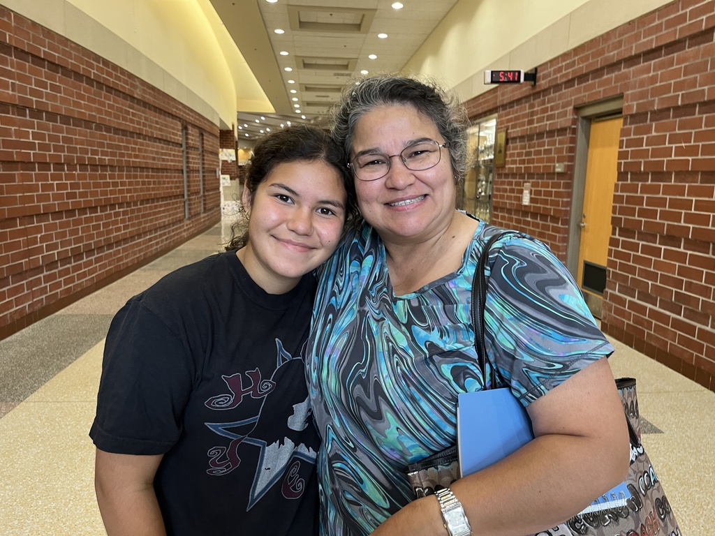 An adult and a  student pose for a photo on a back-to-school night.