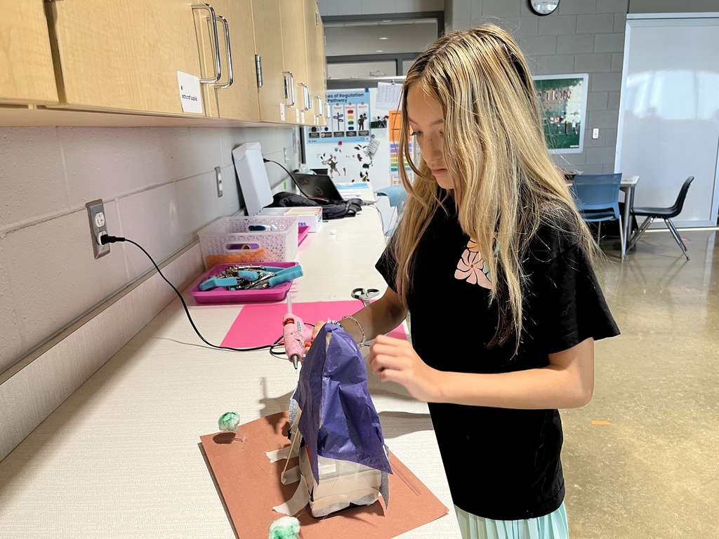 A student in an classroom builds an indigenous home. 