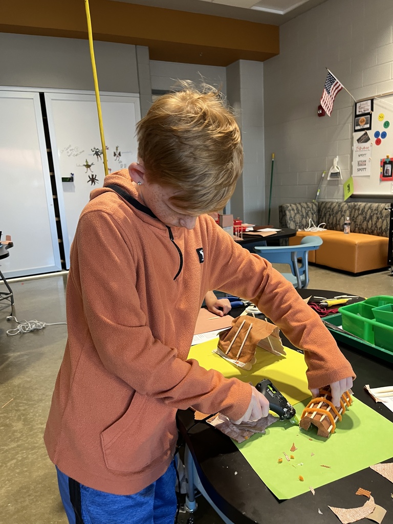 A student in an classroom builds an indigenous home. 