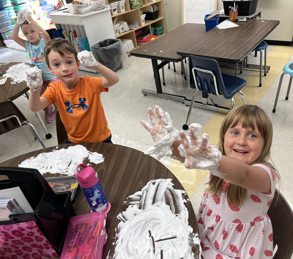 Students practice writing their letters using shaving cream on a desk. 