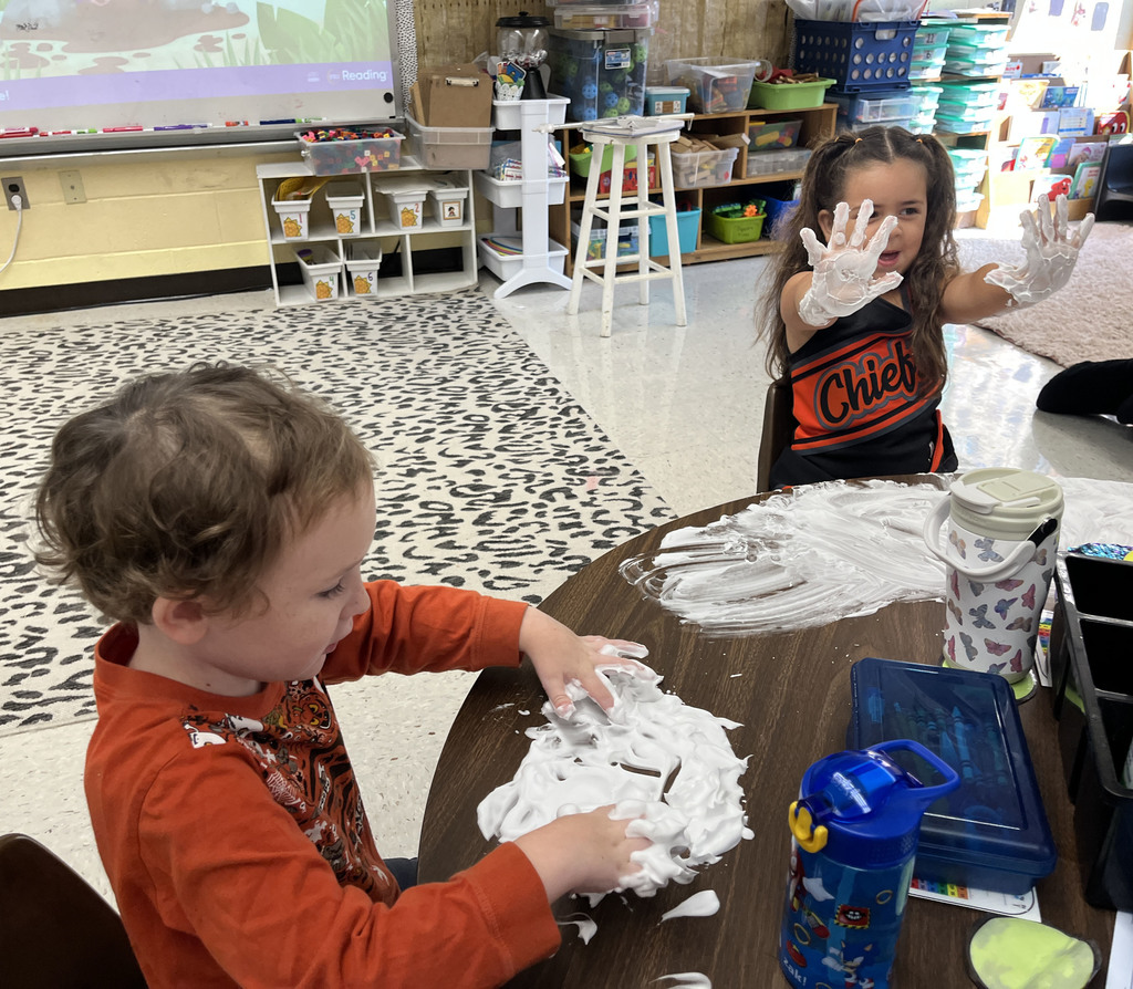 Students practice writing their letters using shaving cream on a desk. 
