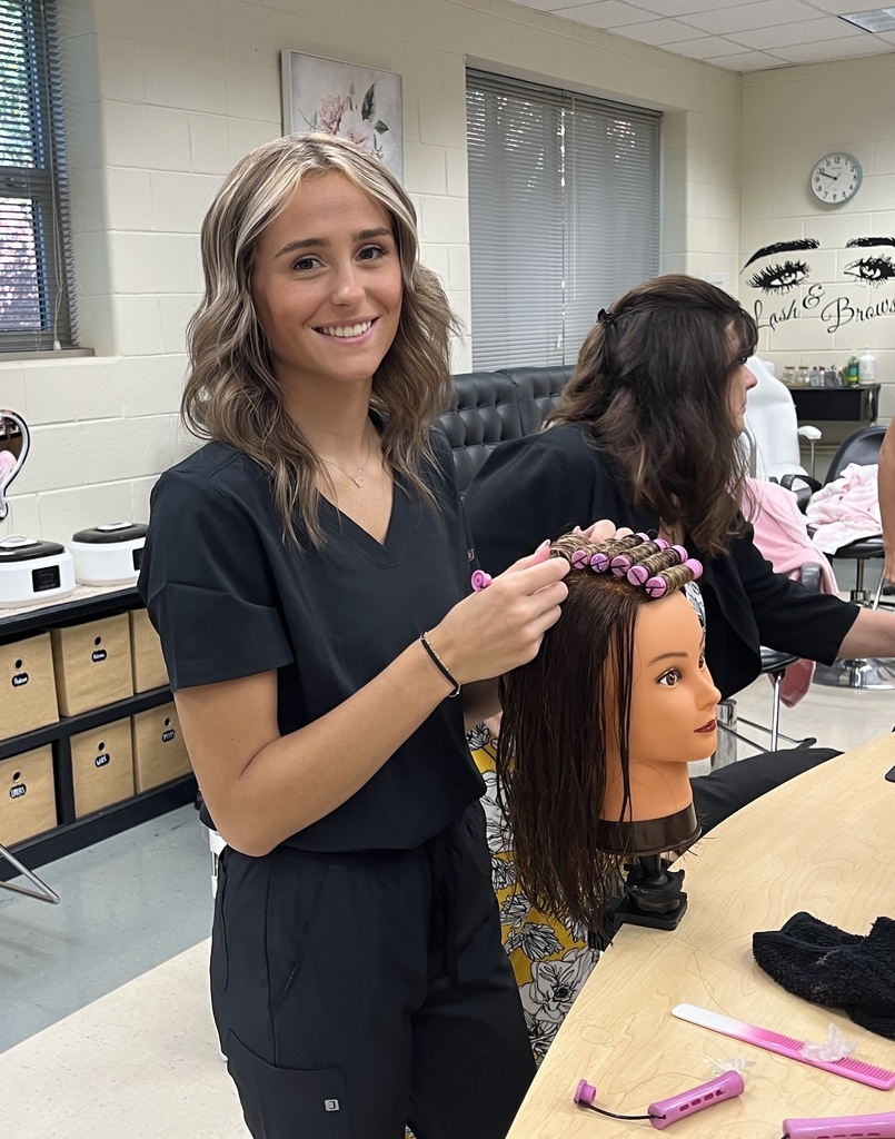 A student uses a cosmetology model head to practice perms. 