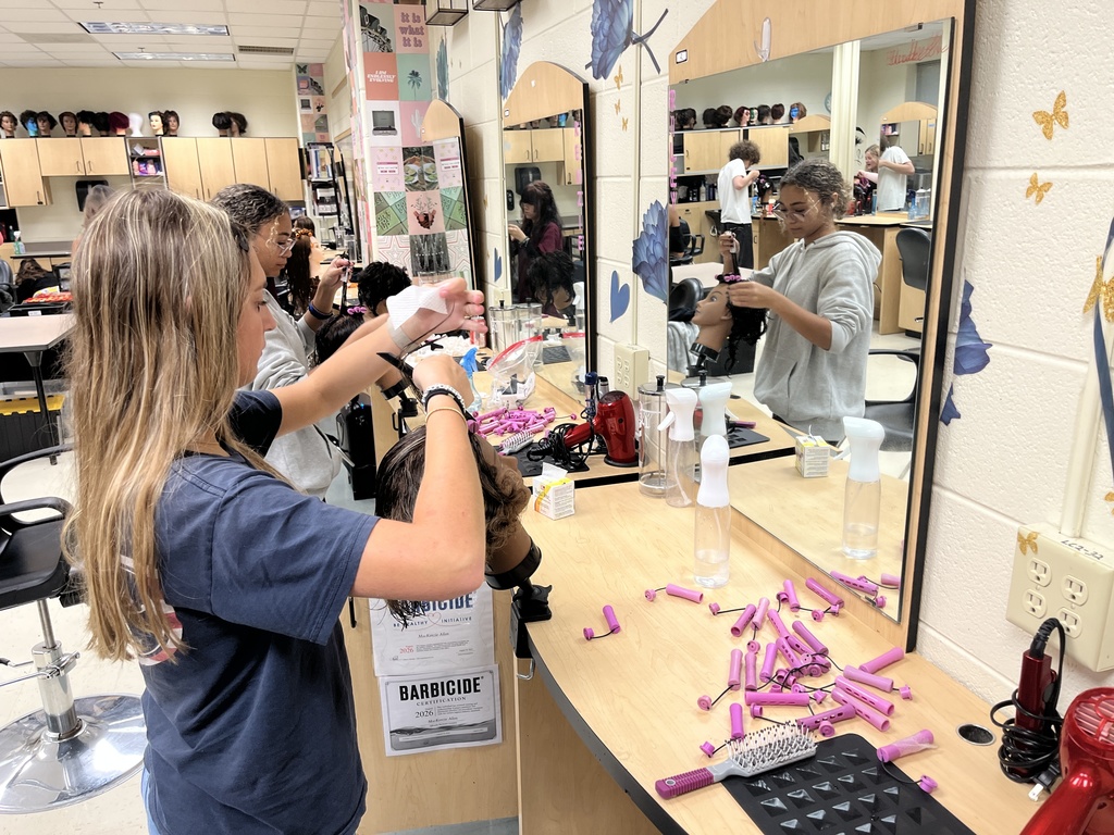 Students use cosmetology model heads to practice perms. 