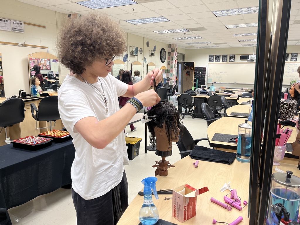A student uses a cosmetology model head to practice perms. 