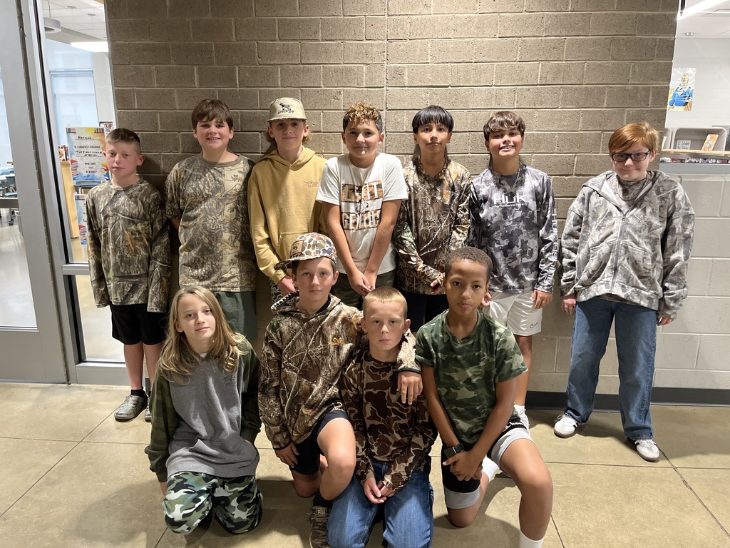 A large group of students pose for a photo showing off attire for Camo Day. 