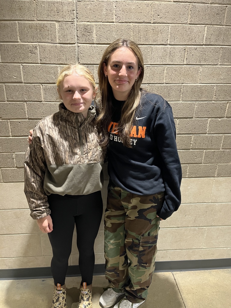 Two  students pose for a photo showing off attire for Camo Day. 