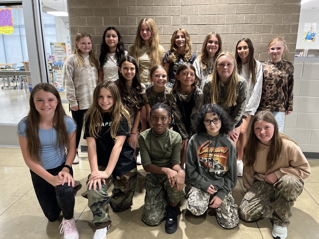 A large group of students pose for a photo showing off attire for Camo Day. 