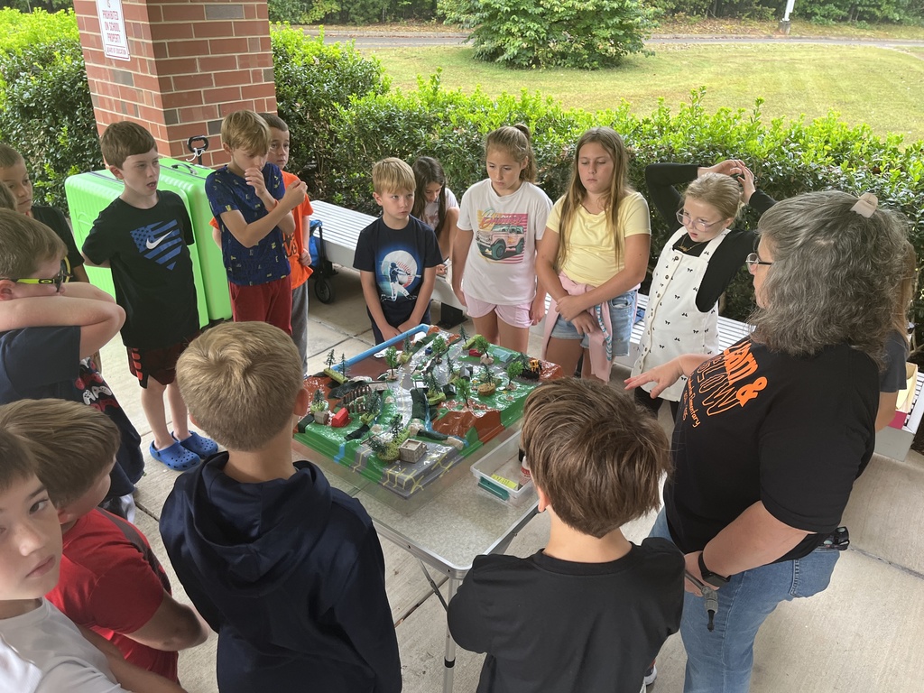 An adult uses a demonstration board to teach a group of students about watersheds.