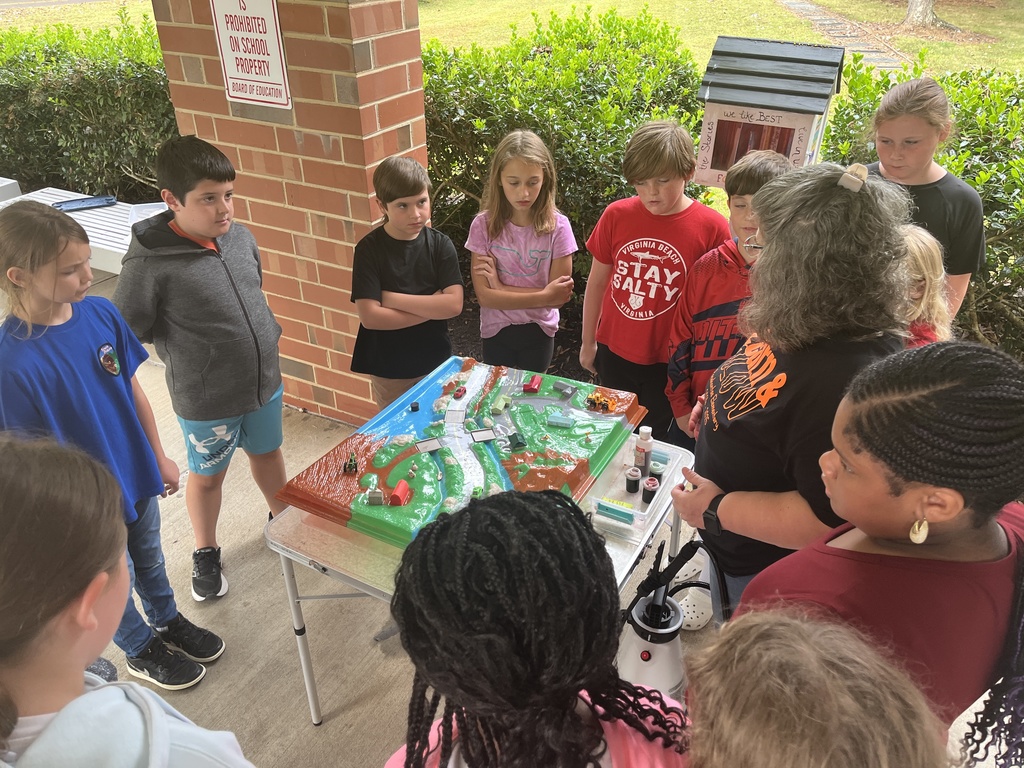 An adult uses a demonstration board to teach a group of students about watersheds.
