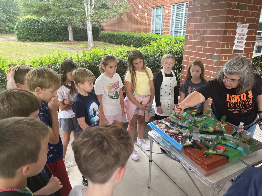 An adult uses a demonstration board to teach a group of students about watersheds.