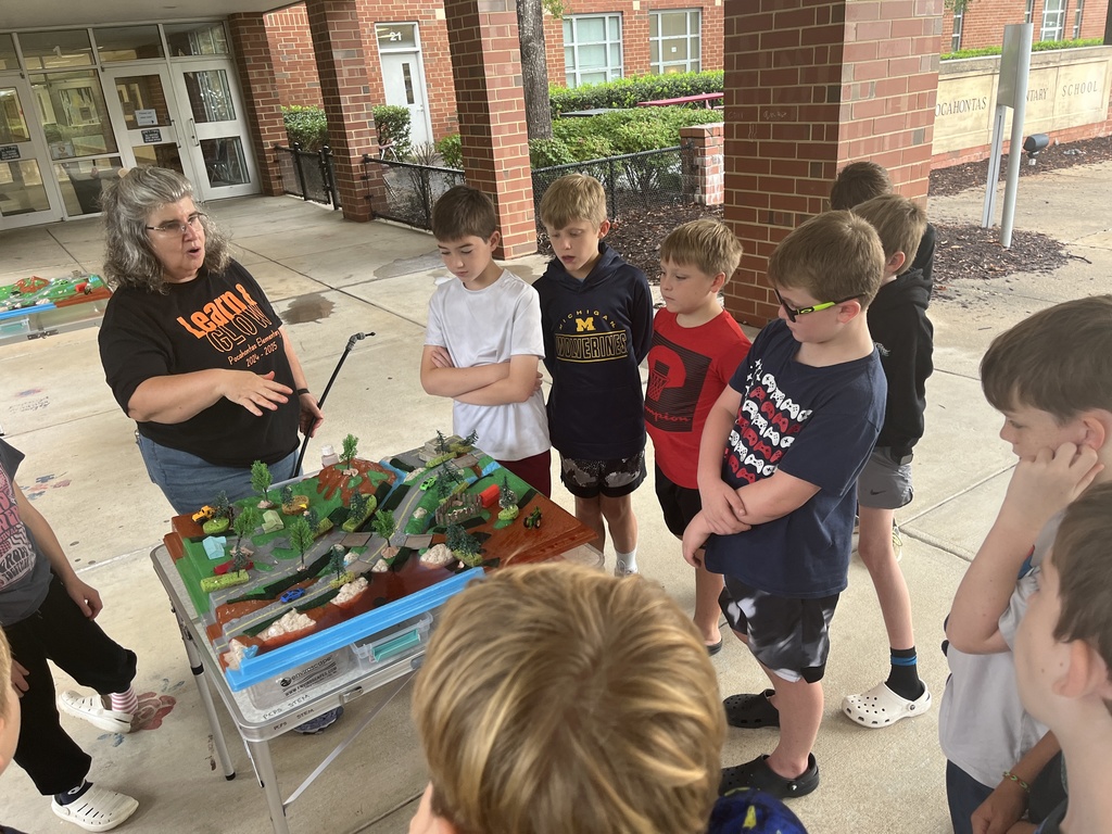 An adult uses a demonstration board to teach a group of students about watersheds.