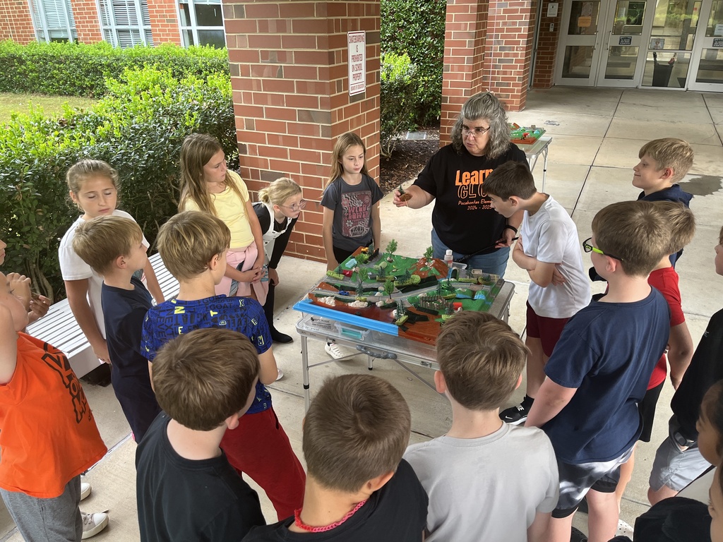 An adult uses a demonstration board to teach a group of students about watersheds.