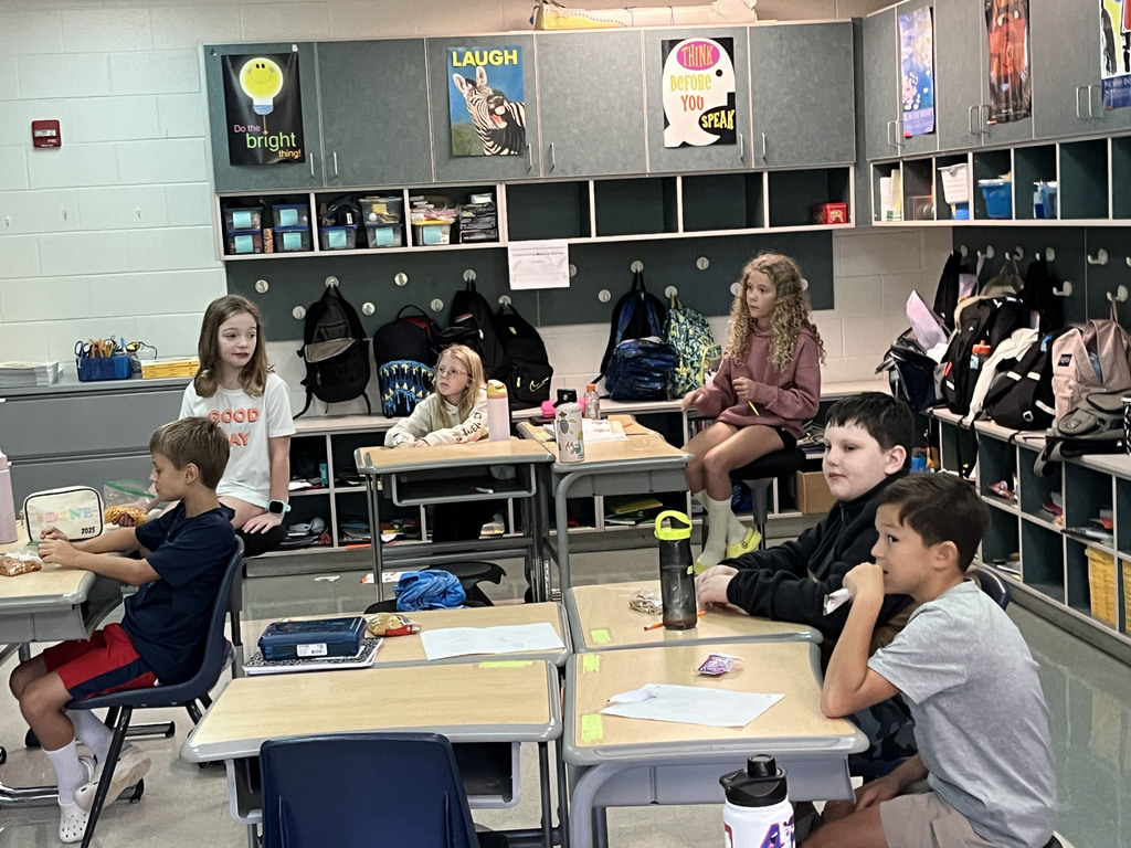 Students listen to their teacher read a book.
