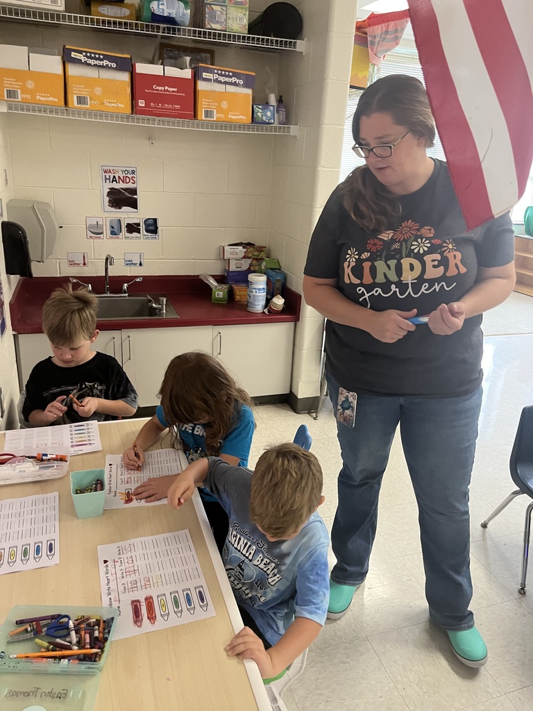 An adult helps kindergarteners working at a literacy station. 