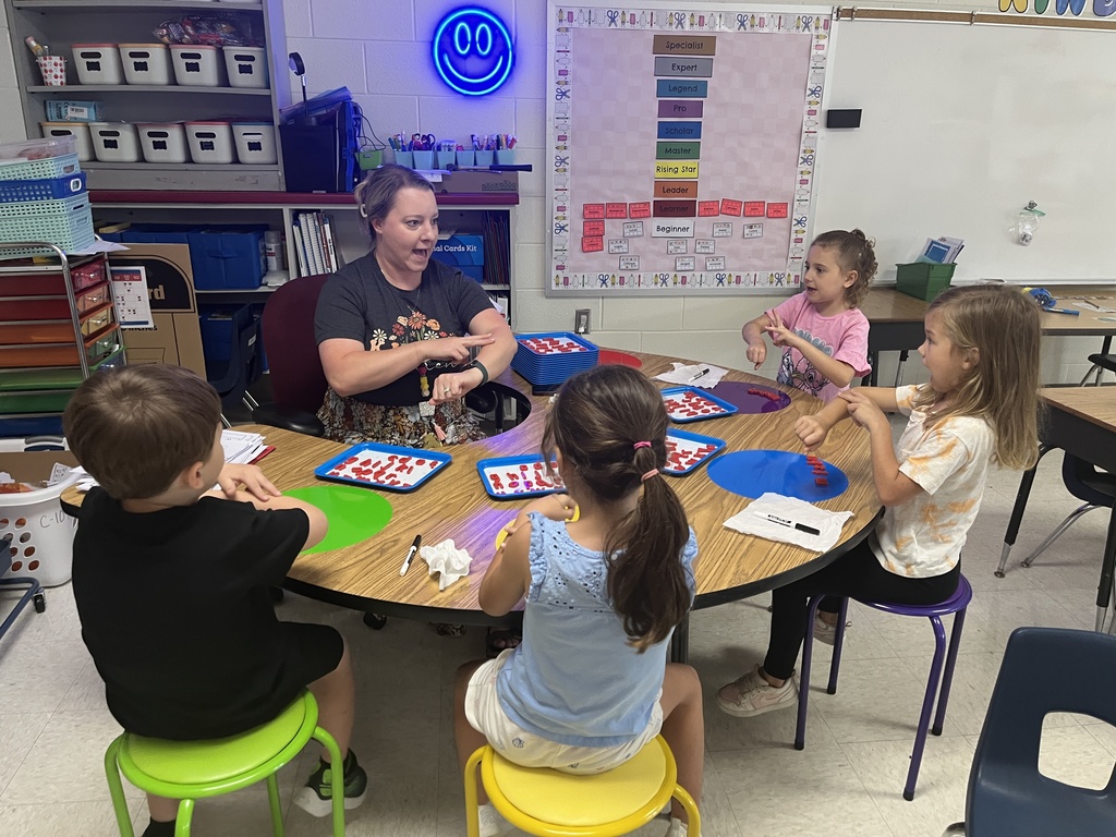 An adult helps kindergarteners working at a literacy station. 