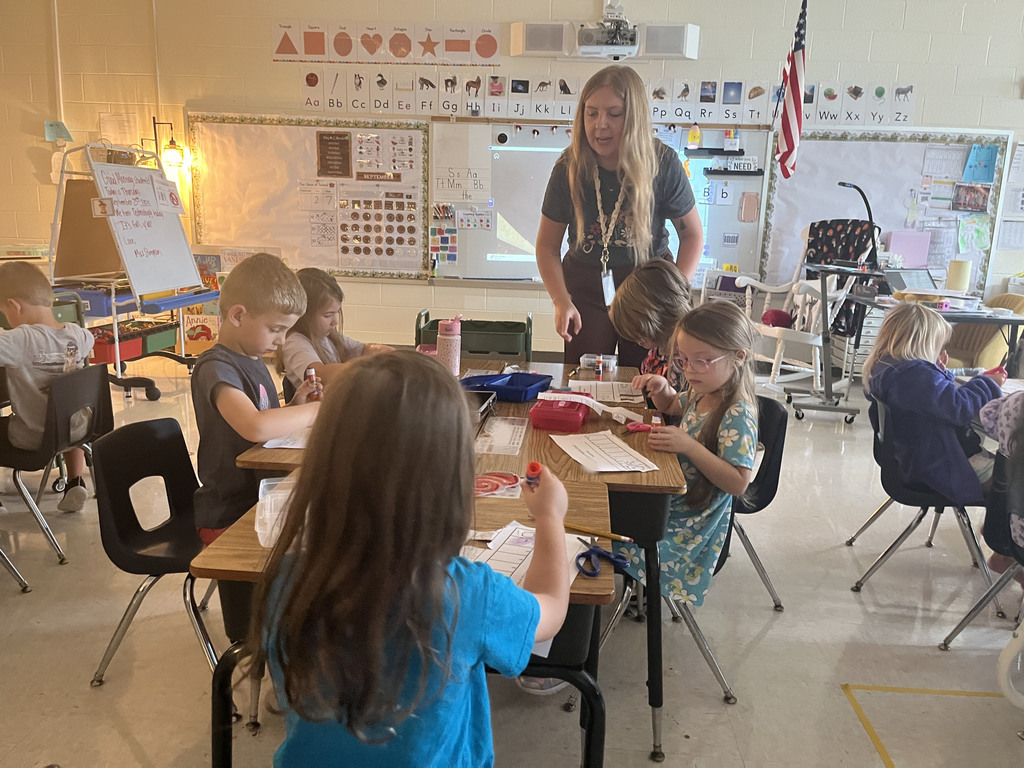 A teacher helps students as they work on a sequencing activity.