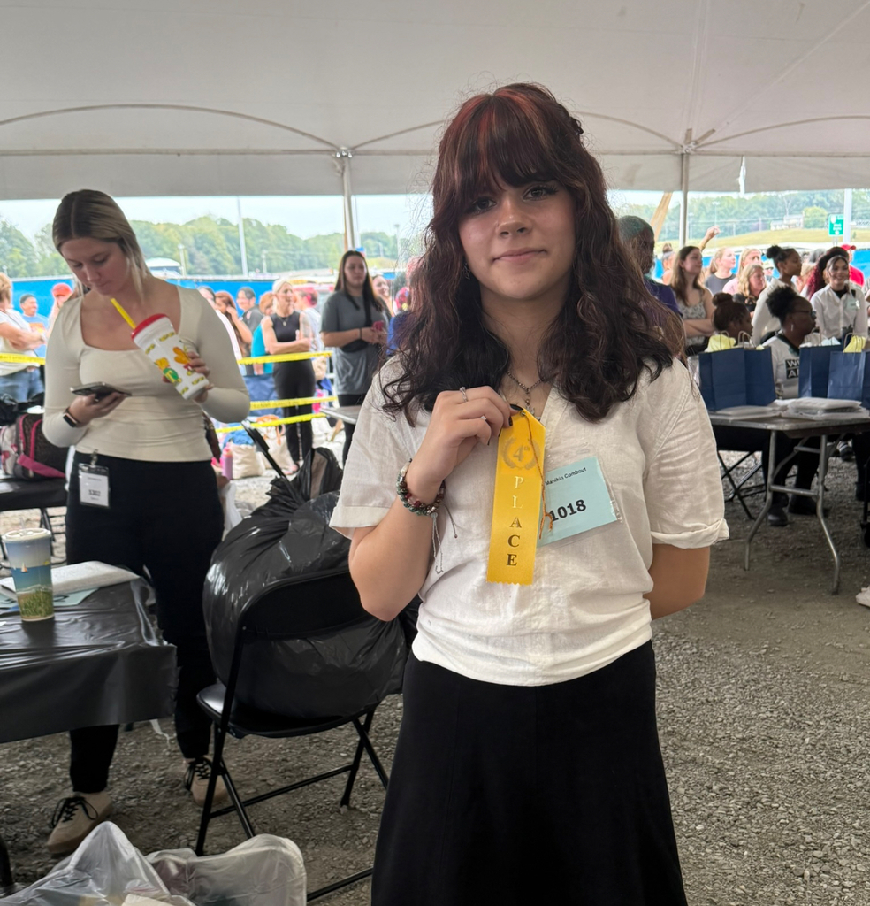A student holds up a 4th place ribbon.