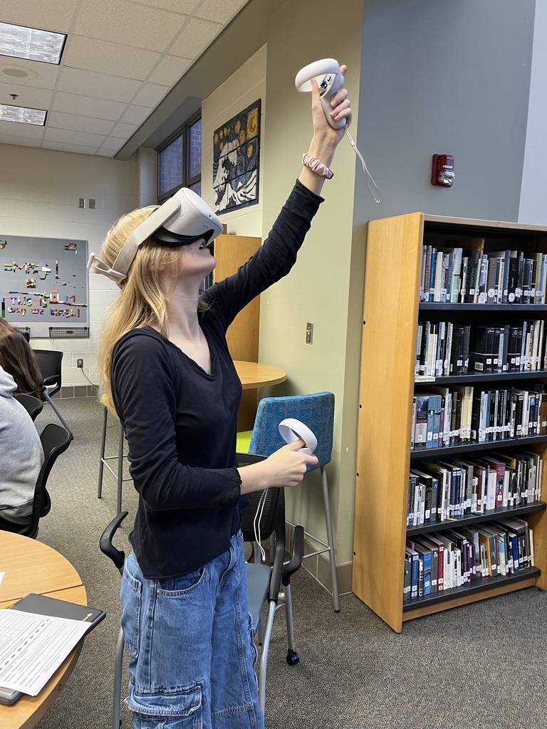 A student uses VR goggles in a library.
