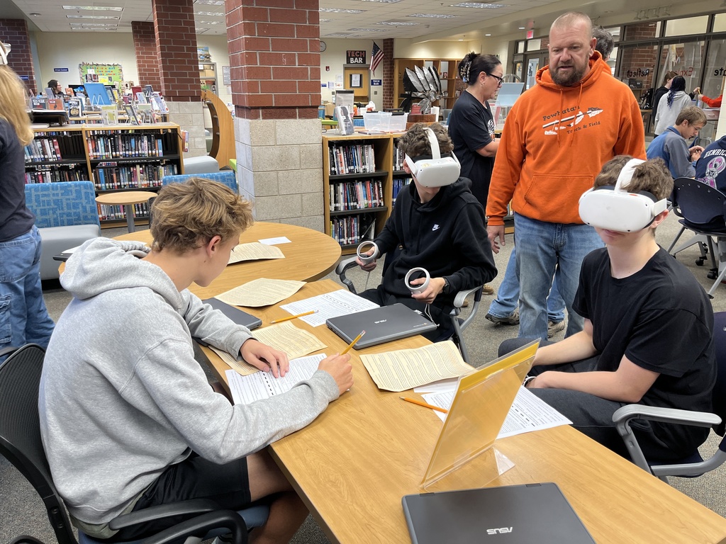 A group of students work at a station dealing with migration and using VR goggles.
