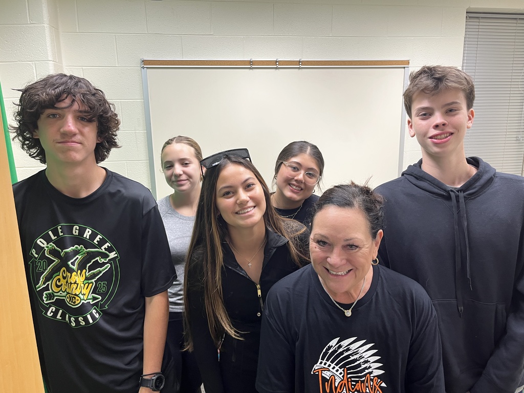 A teacher and a group of students pose for a photo.