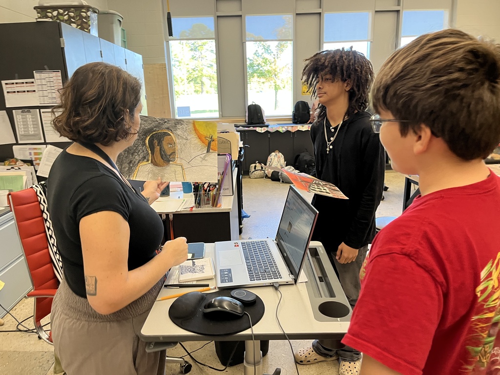 Students show their art teacher portraits they are creating.