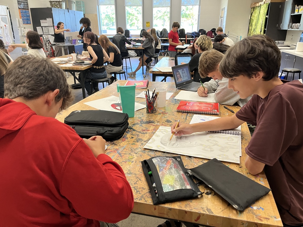 Students in art class work work on portrait assignment.