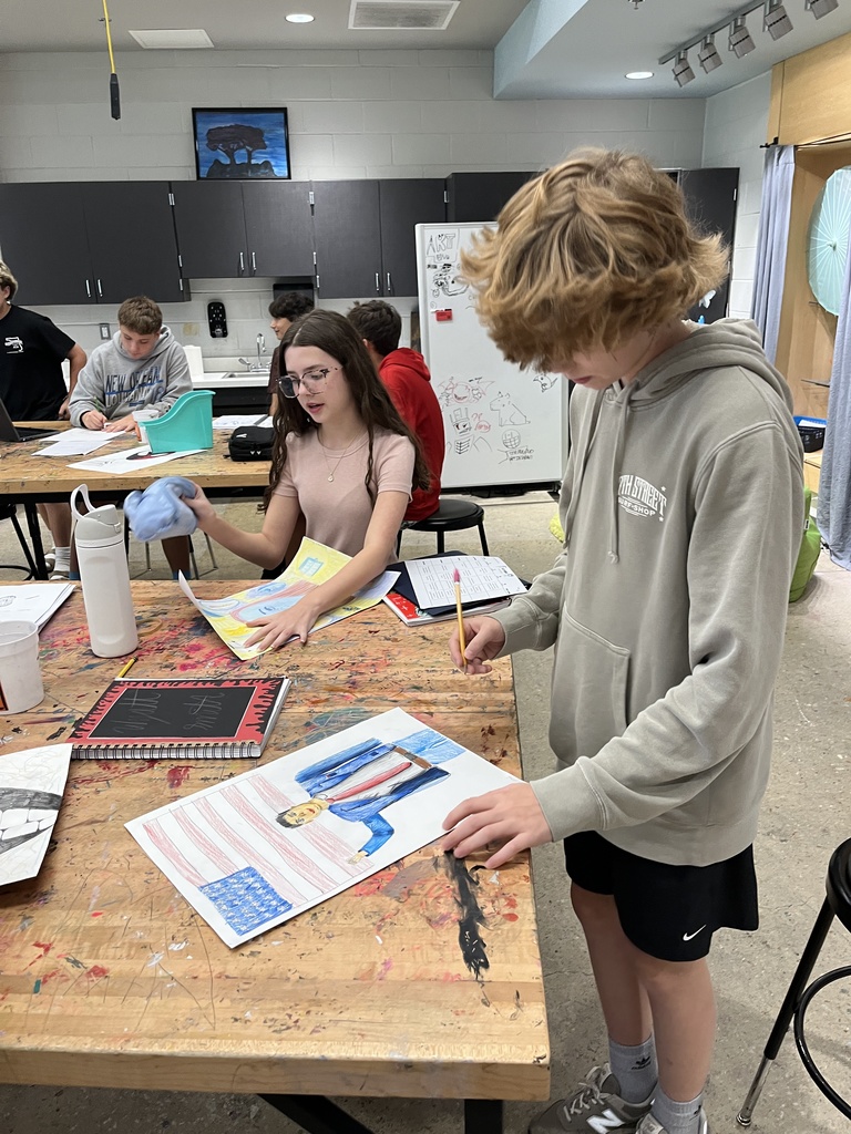 Students in art class work work on portrait assignment.