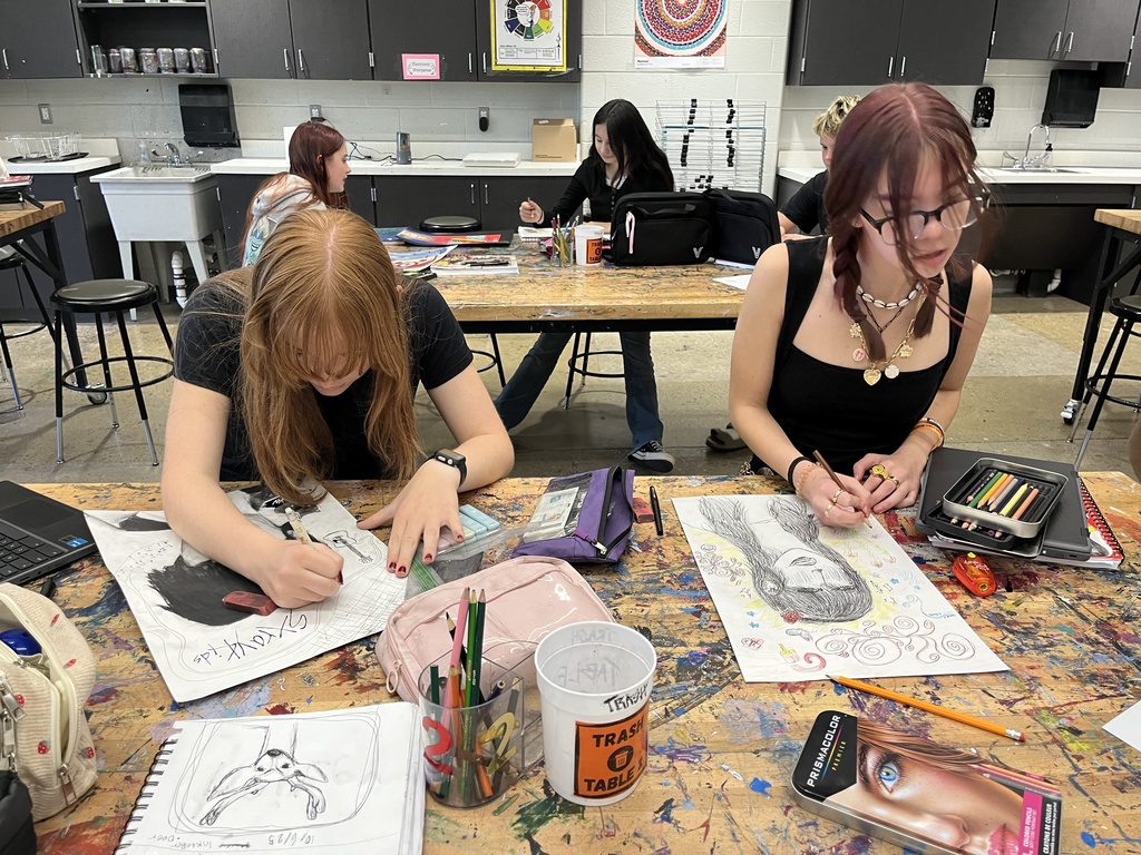 Students in art class work work on portrait assignment.
