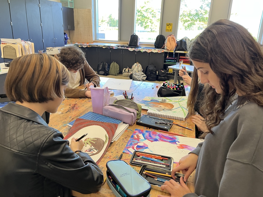 Students in art class work work on portrait assignment.