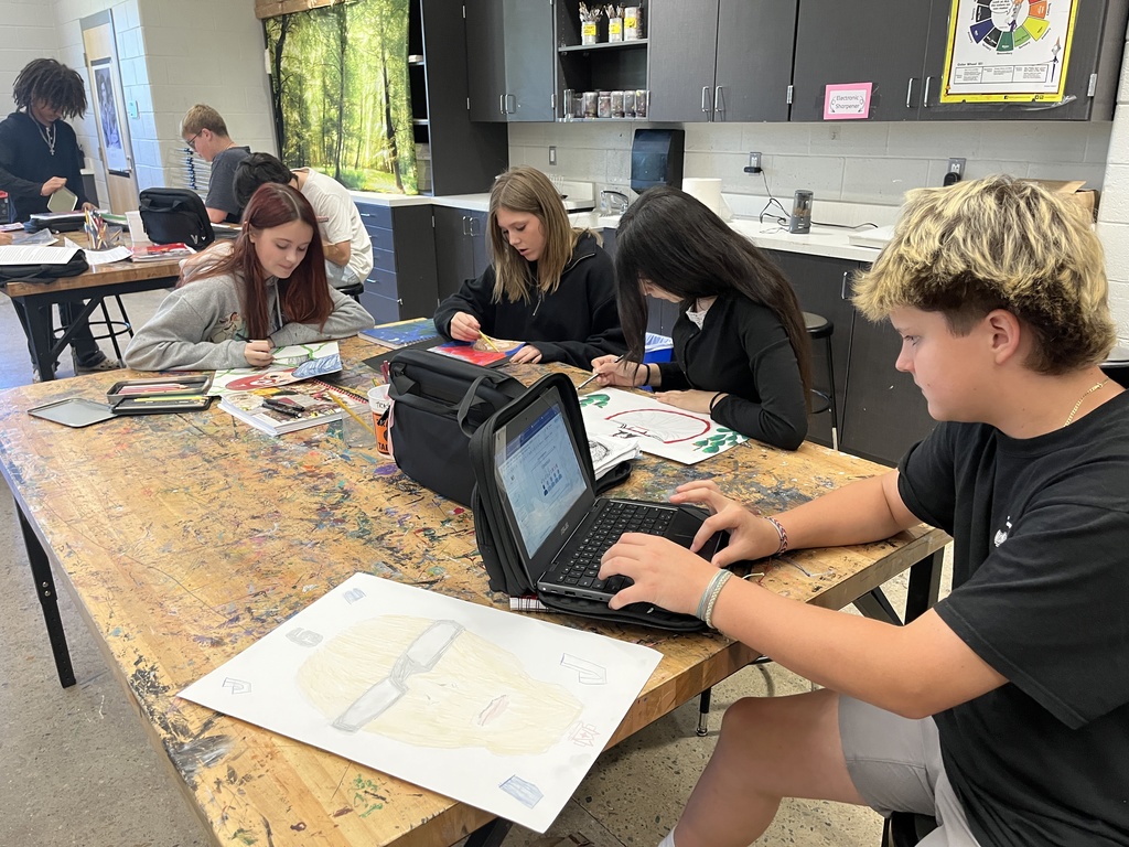 Students in art class work work on portrait assignment.