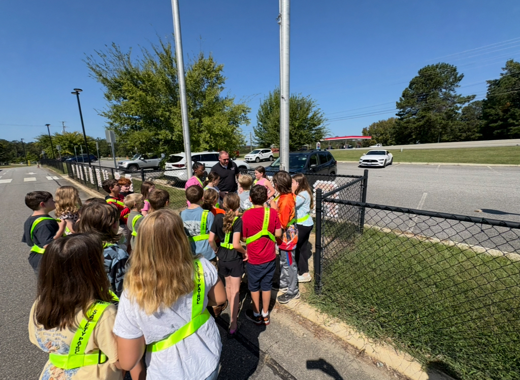 Student safety patrol members receive instructions from an adult on raising the flags.