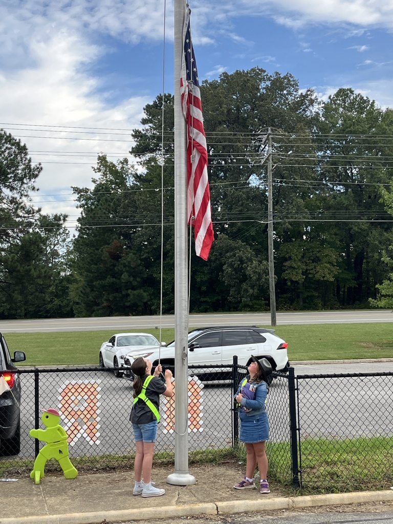 Student safety patrol members raise the flag.