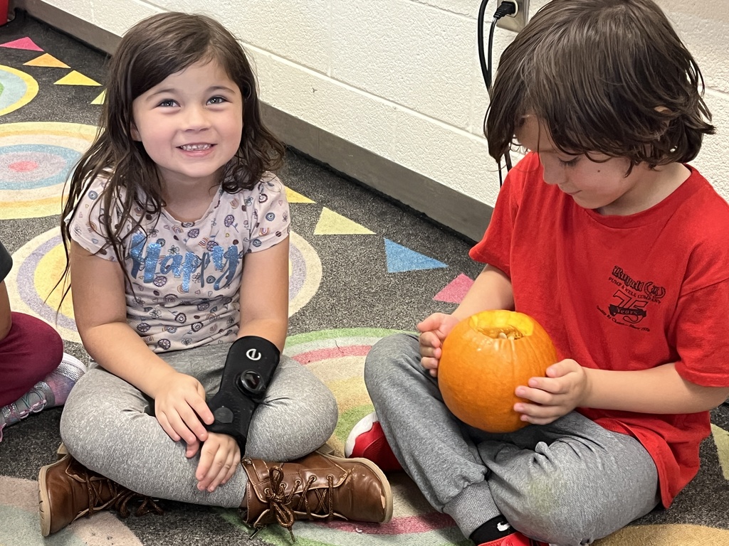 Children take turns feeling the inside of a pumpkin in class. 
