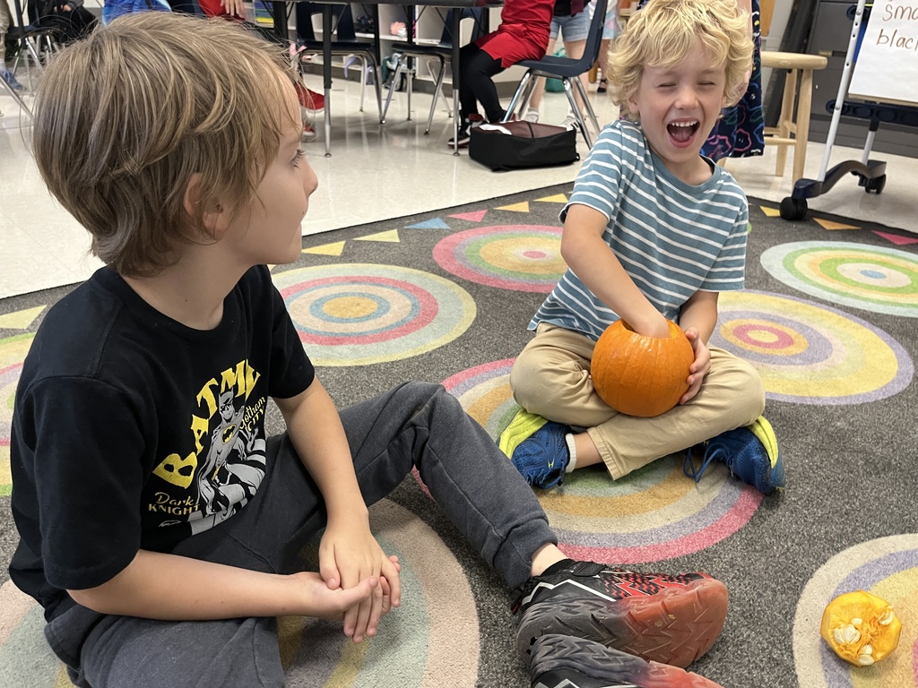 Children take turns feeling the inside of a pumpkin in class. 
