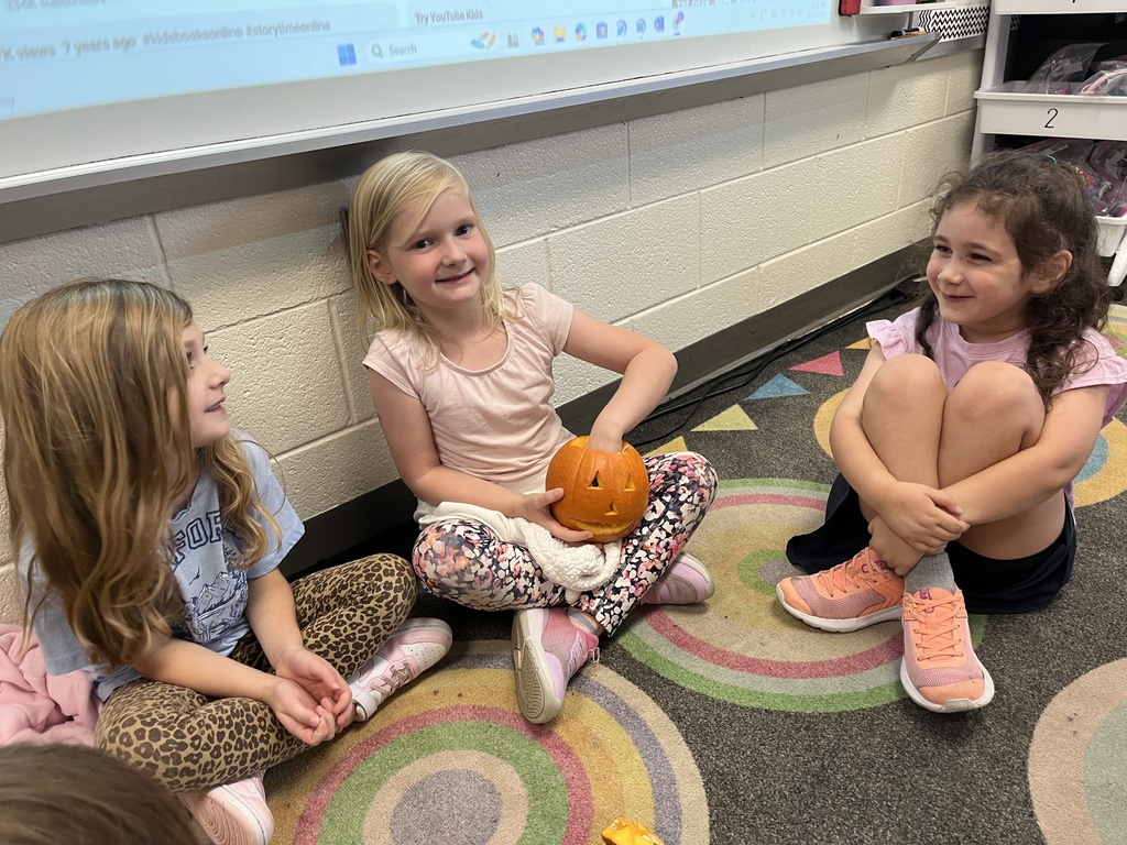 Children take turns feeling the inside of a pumpkin in class. 