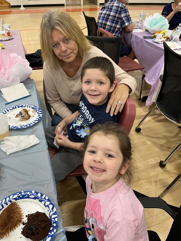 One adult and two children pose for a photo at a grandparents breakfast. 