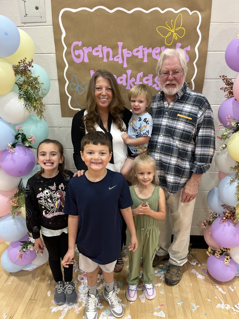 Two adults and four children pose for a photo at a grandparents breakfast. 