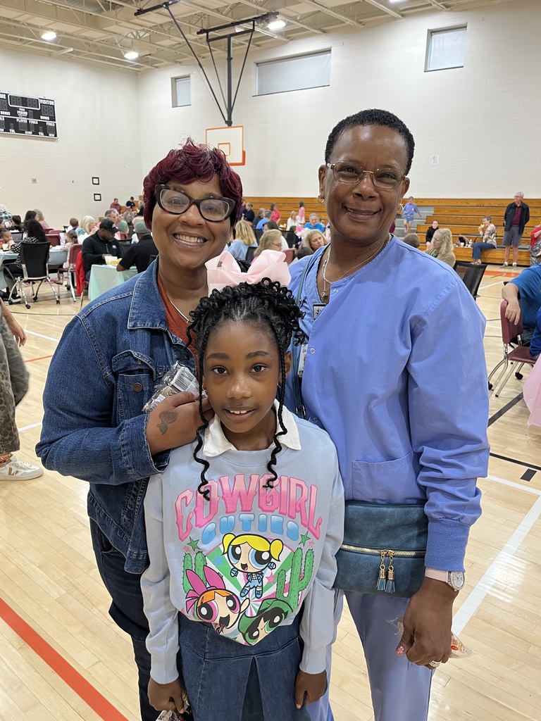 Two adults and one child pose for a photo at a grandparents breakfast. 