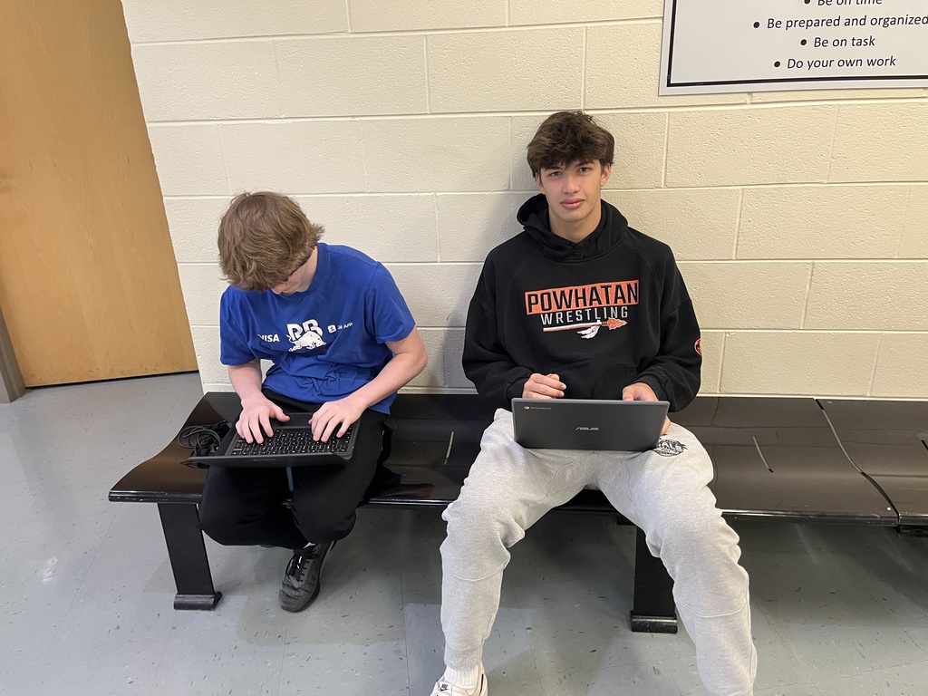 Students work in groups on a practical law assignment in a school hallway.