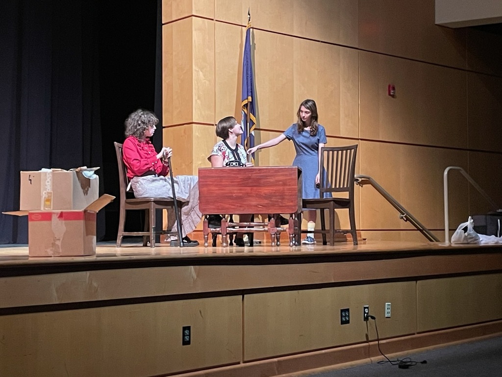 Three students perform in a one-act play in a high school theater.