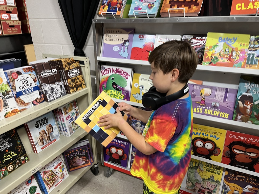 A student searches through merchandise at a school book fair. 