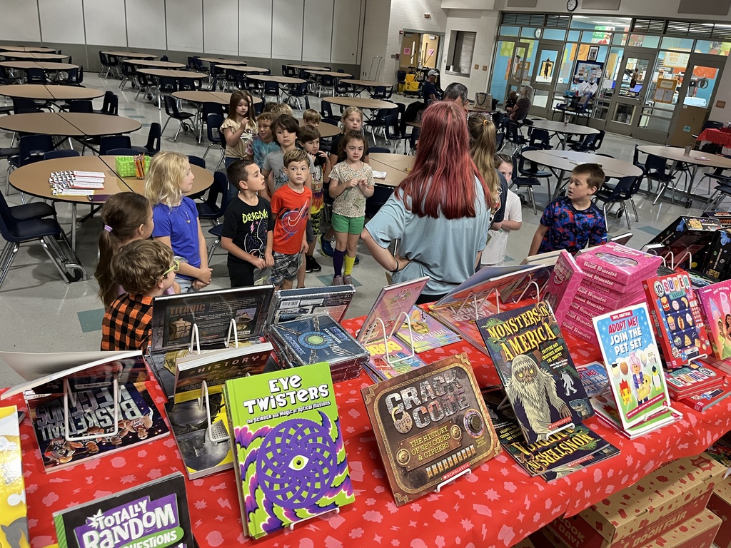 An adult explains the rules of a book fair to a class. 