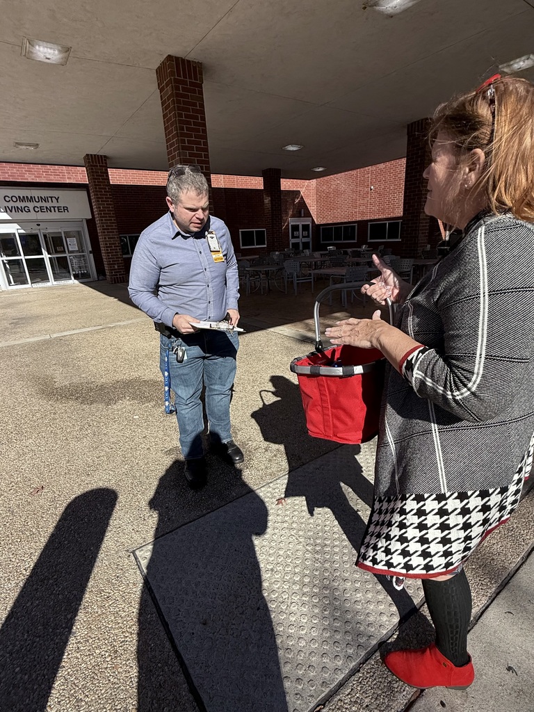 A woman presents a  bag of veterans day cards to a man.
