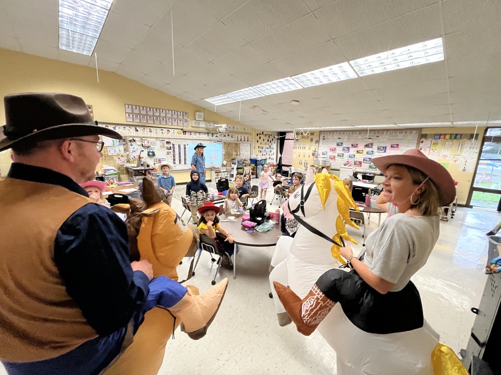 Two administrators in horse and rider costumes interact with children.