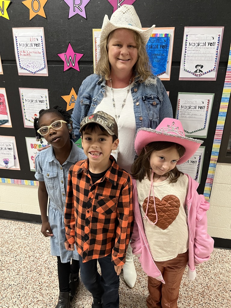 A teacher and children in western wear pose for a photo.