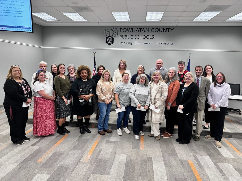 A large group of men and women pose for a group photo. Some are holding checks for grants.