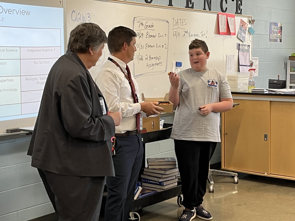 Two adults and a student speak during a fidget spinner donation.