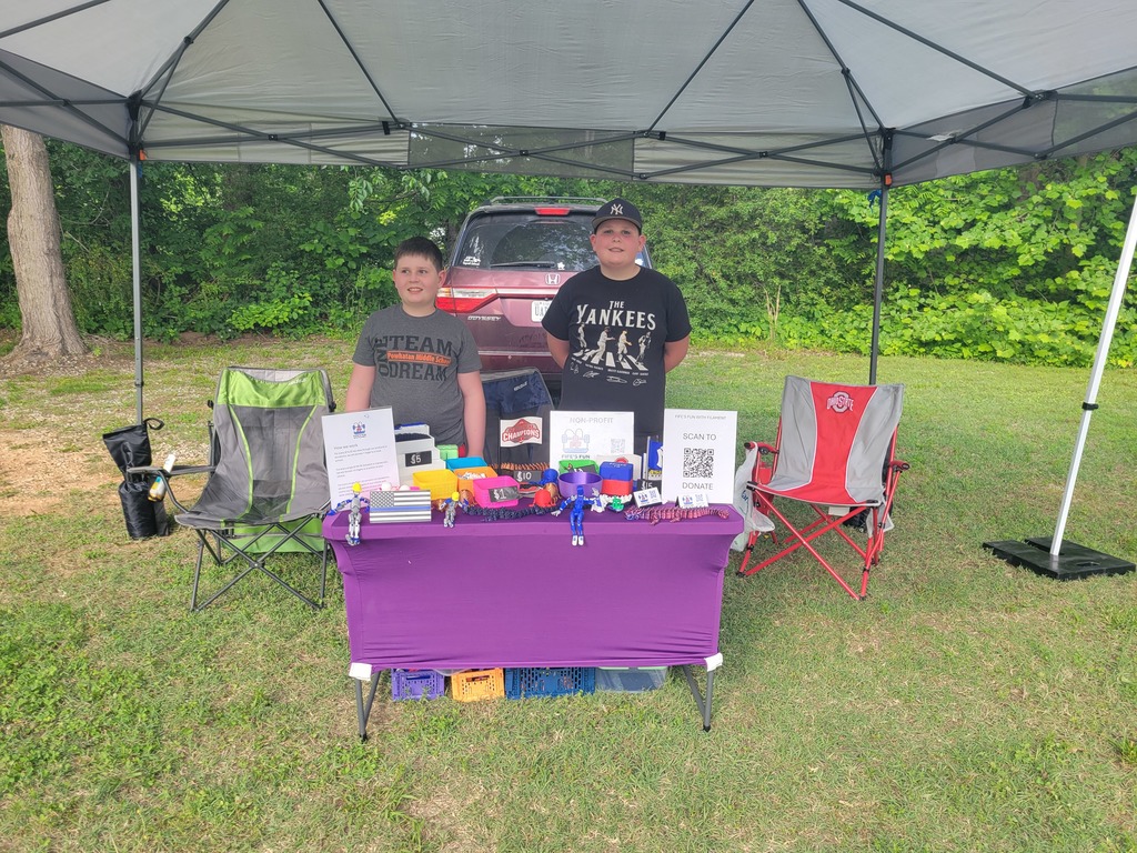 Two children sell fidget spinners at an outdoor market.