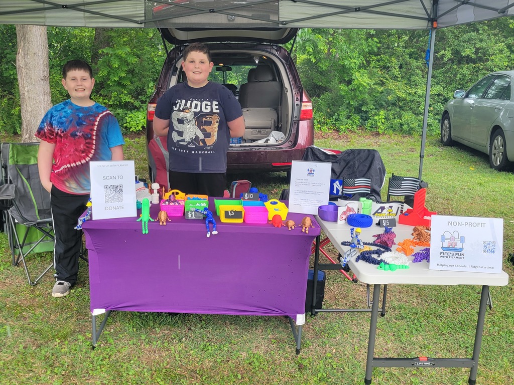 Two children sell fidget spinners at an outdoor market.